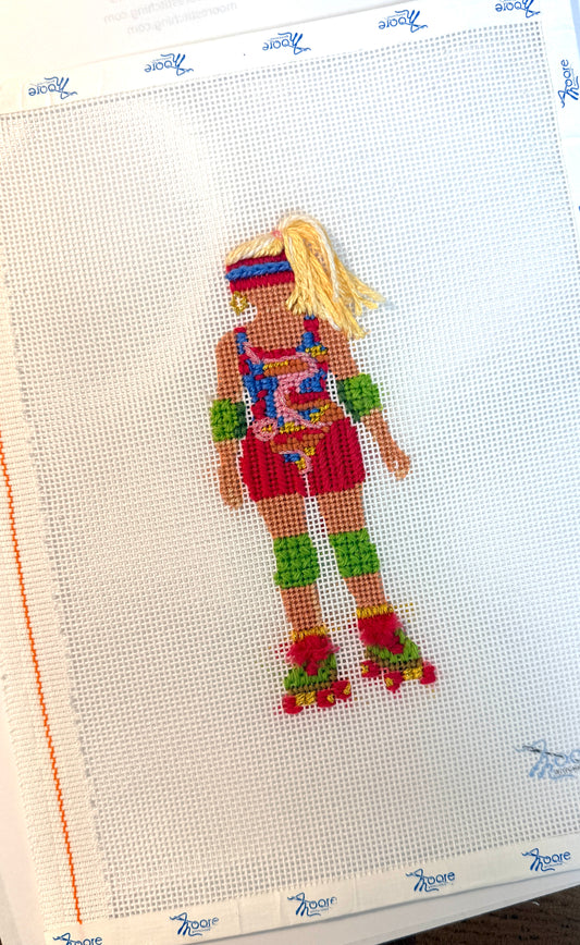 Cross-stitched design of a colorful character on fabric with a white background