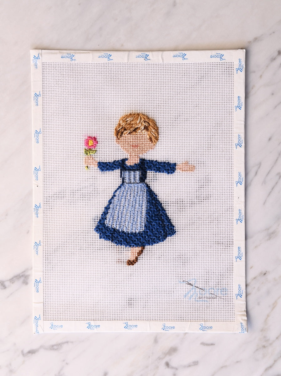Cross-stitched picture of a girl holding a flower on a white background