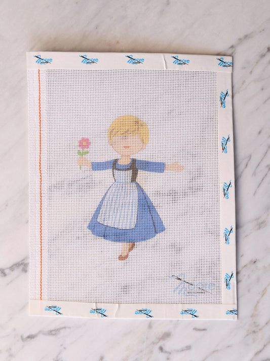Cross-stitched design of a girl in a blue dress on fabric.