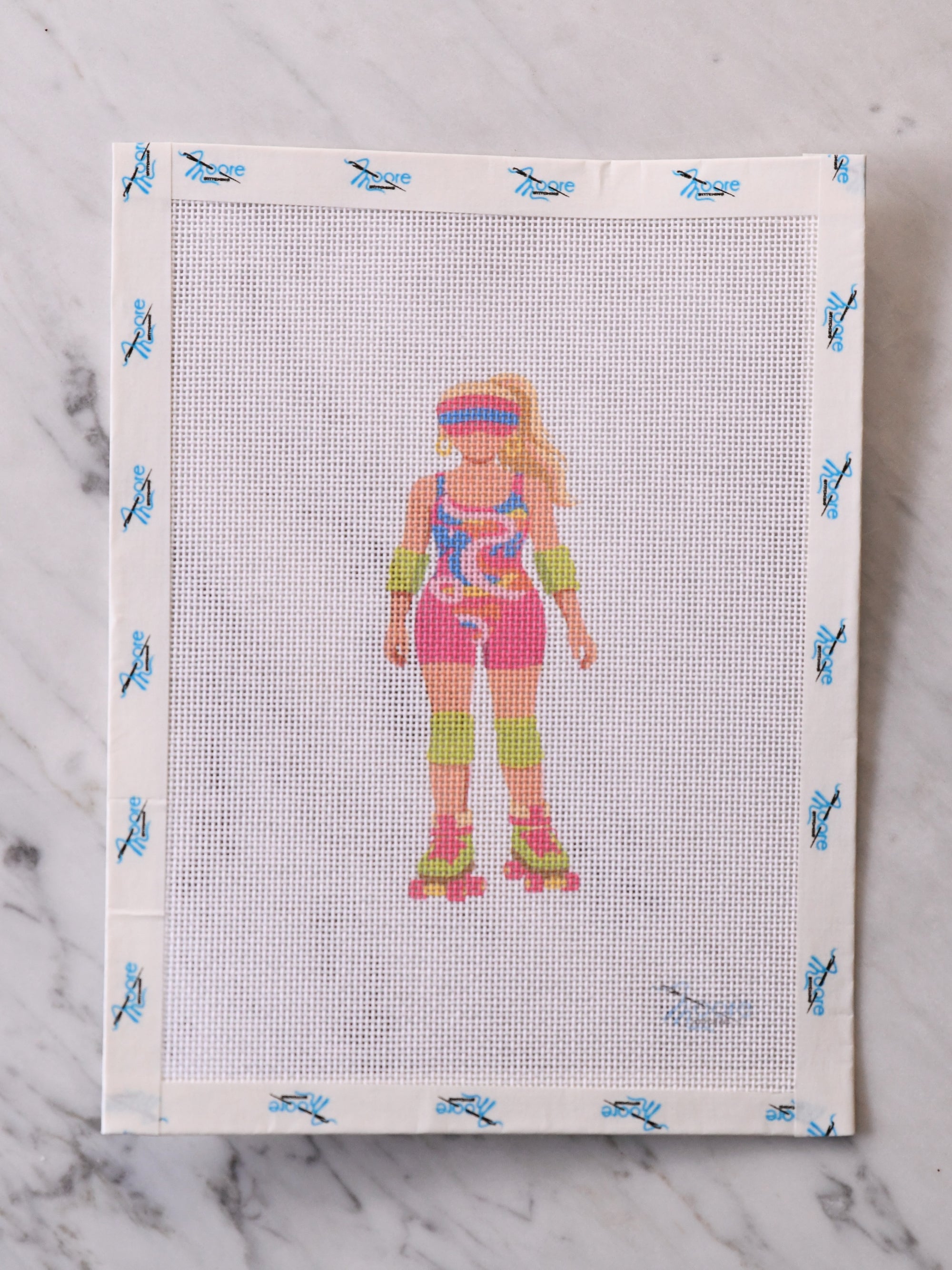 Cross-stitched pattern of a person roller skating on fabric with blue butterfly designs.