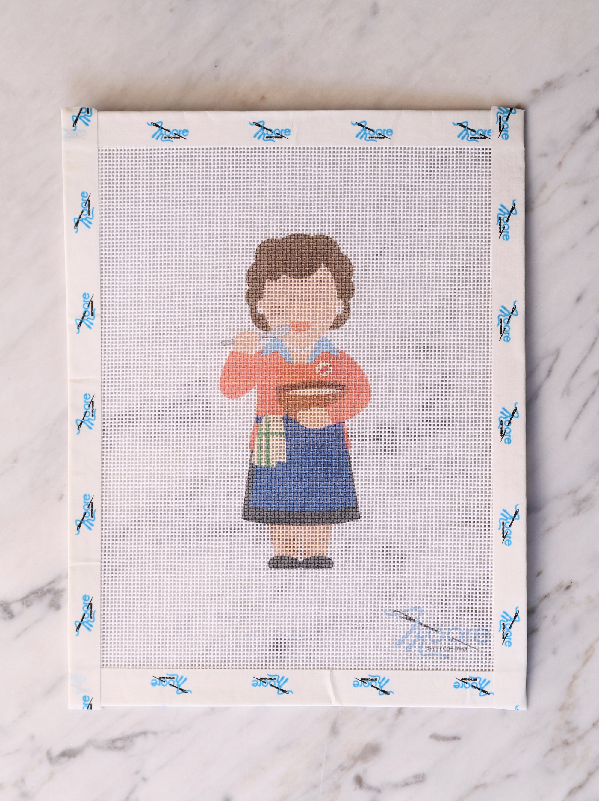 Cross-stitch design of a woman holding a bowl and spoon on a white fabric background