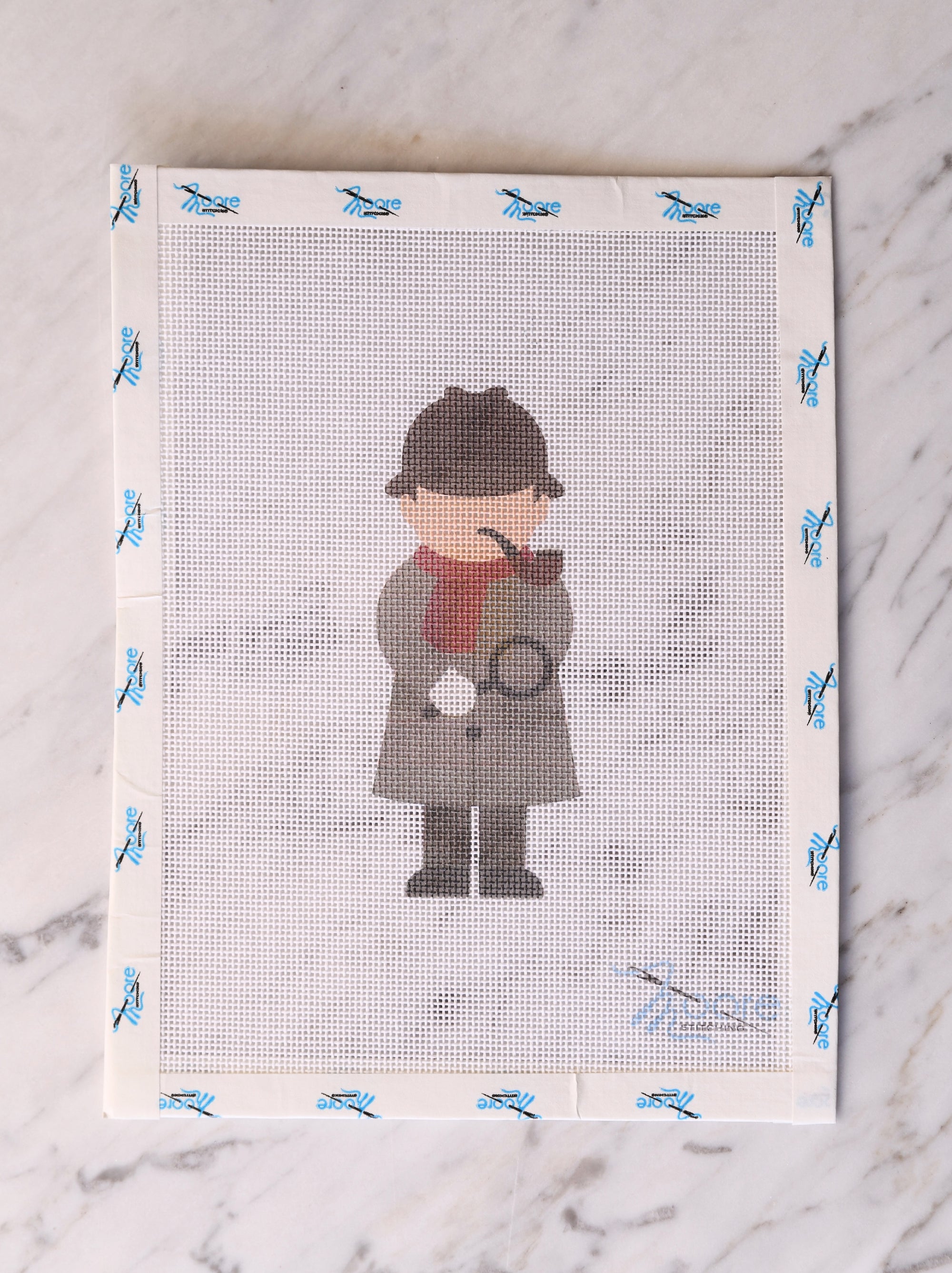 Cross-stitched design of a detective on fabric with a marble background