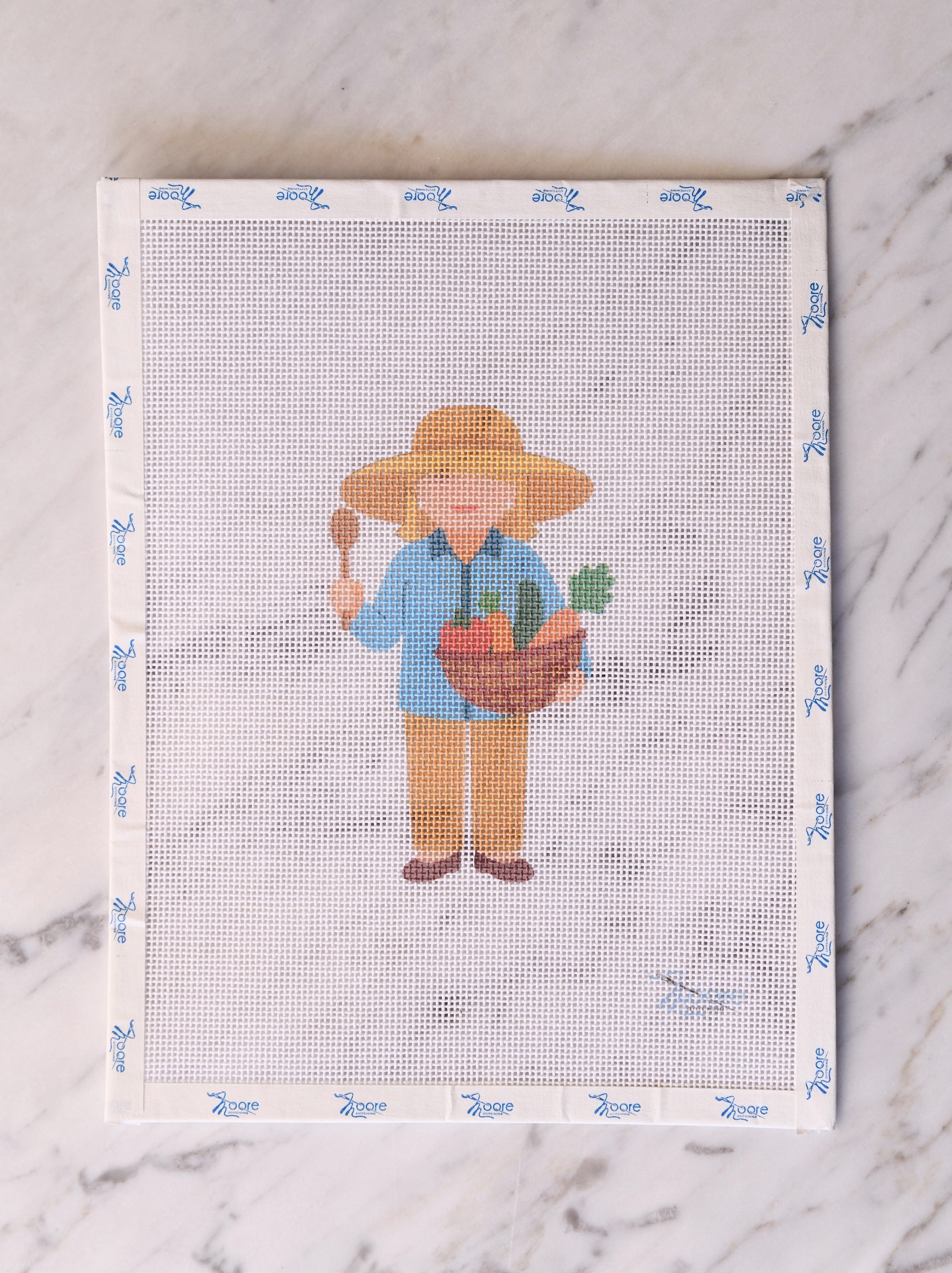 Cross-stitch pattern with a gardener holding a basket of vegetables on a white background