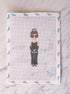 Cross-stitched design of a woman in a black dress and hat on fabric.