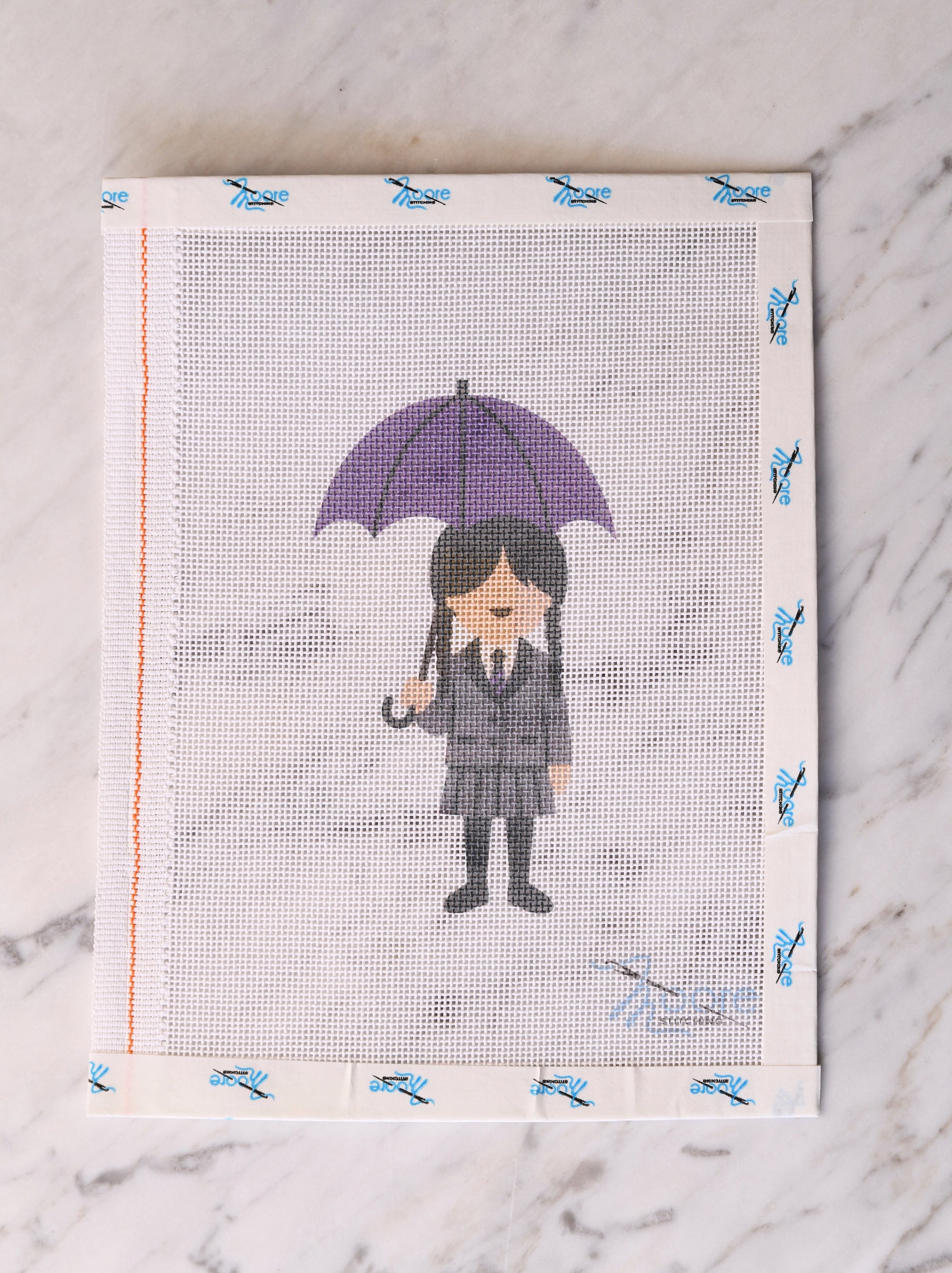 Cross-stitched design of a person with a purple umbrella on fabric.