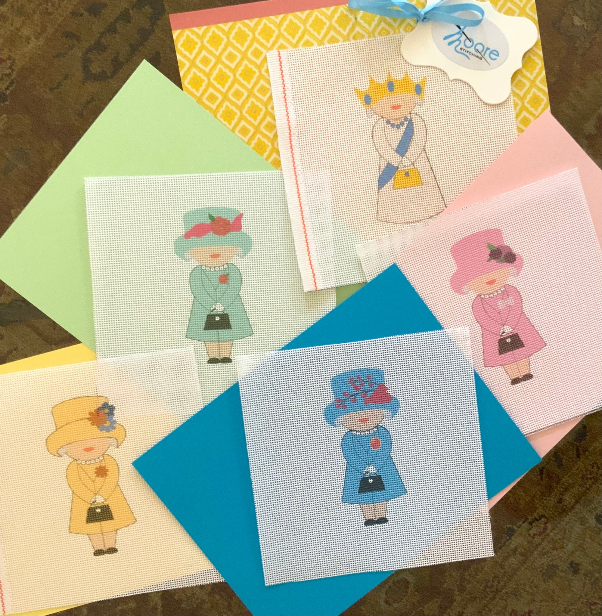 A collection of colorful mesh needlepoint canvas designs of 5 queen characters, each wearing a different dress.