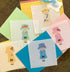 A collection of colorful mesh needlepoint canvas designs of 5 queen characters, each wearing a different dress.